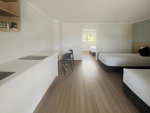 a hotel room with a bed and a desk and a bed and a room at Albany Oak Motel in Auckland