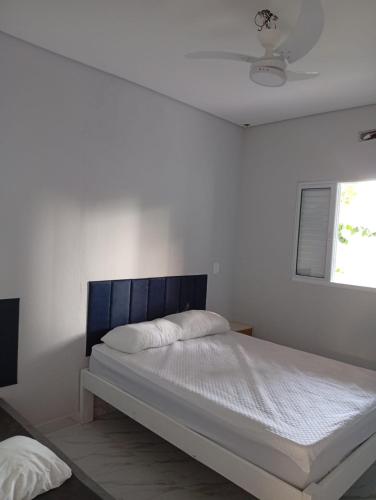 - une chambre avec un lit doté d'une tête de lit bleue et d'une fenêtre dans l'établissement Recanto Amora, à Boicucanga