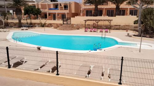 a large swimming pool in a resort with trees and a building at Paraíso en Fuerteventura in Costa Calma