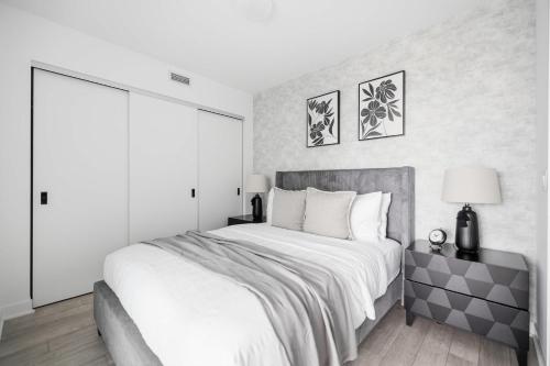 a white bedroom with a large bed with white sheets at Stylish 2BR Retreat Parking & Sleeps 6 in Toronto