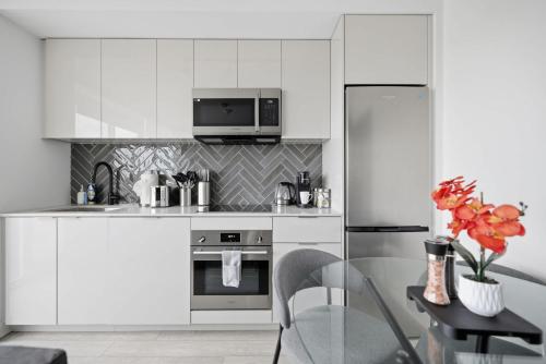 a kitchen with white cabinets and a stainless steel refrigerator at Stylish 2BR Retreat Parking & Sleeps 6 in Toronto