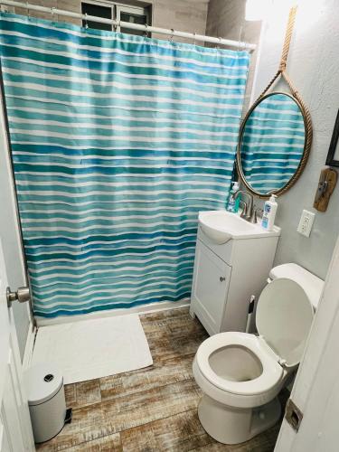 a bathroom with a toilet and a blue shower curtain at Northeast Investments LLC in Gulfport