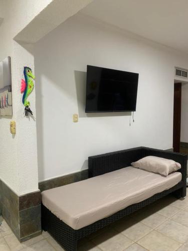 Habitación con sofá y TV en la pared. en Conjunto Residencial Emerald Suites, en Tucacas