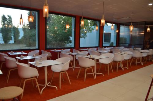 a restaurant with tables and chairs and large windows at Hôtel ibis Styles Auxerre Nord in Auxerre
