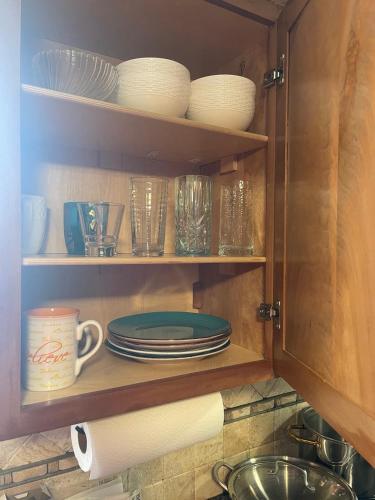 a kitchen cabinet filled with plates and cups and dishes at Splendid Room in House 10 mins to Airport in Saint Louis