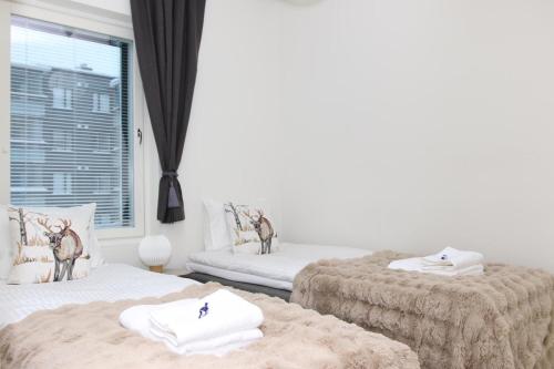 two twin beds in a room with a window at Arctic Aurora Suite Rovaniemi in Rovaniemi