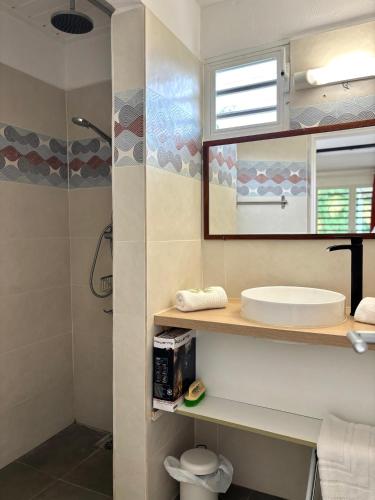 a bathroom with a sink and a mirror and a shower at Tika Bungalow - Pisicne, Wifi, Grande Terrasse privée et Accès Plage à pied in Grand-Bourg