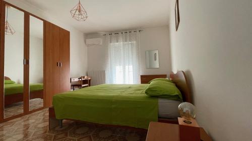 a bedroom with a green bed and a window at La Finestra sul Borgo in Campomarino