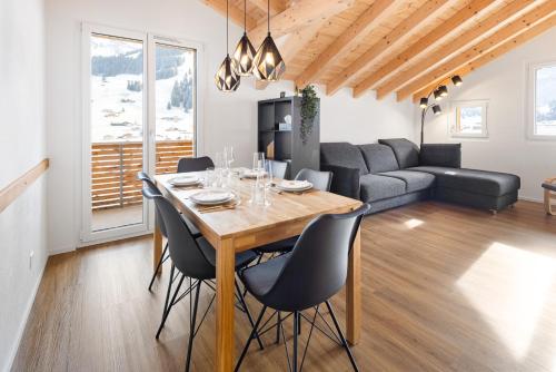 ein Esszimmer und ein Wohnzimmer mit Tisch und Stühlen in der Unterkunft Chuenislodge2- zwei Balkone, gemütlicher Kamin, top Aussicht in Adelboden