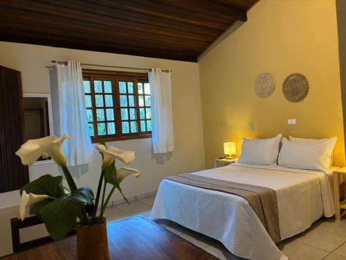 a bedroom with a white bed and a window at Pousada Roca in Ibiúna