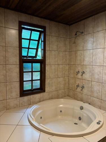 a bath tub in a bathroom with a window at Pousada ROCA in Ibiúna