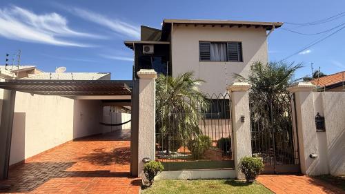 a white house with a gate and a fence at Quarto casal coliving 2 in Dourados