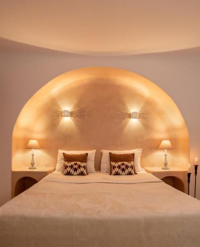 a bedroom with a large white bed with two pillows at Palmariva Villas in Fira