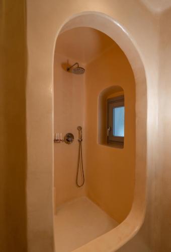 a bathroom with a shower with a round mirror at Palmariva Villas in Fira