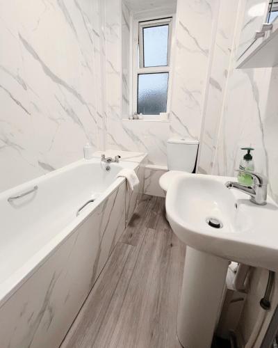 une salle de bain blanche avec une baignoire et un lavabo dans l'établissement Leith Apartment, à Édimbourg