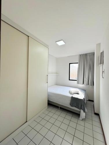 Una habitación blanca con una cama y una ventana. en Edifício Atlantis Hotel, en Maceió