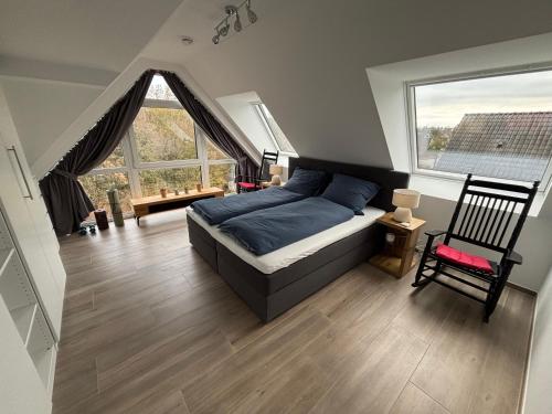 a bedroom with a bed and a chair and windows at Luxuriöse Maisonette Wohnung mit Whirlpool und Weitblick im Kurviertel von Bad Salzuflen in Bad Salzuflen