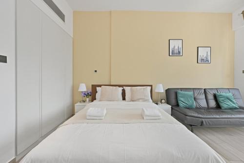 a large white bed in a room with a couch at Dubai JVC - Oxford Residence 2 - Parking&Balcony in Dubai