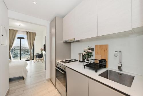 a kitchen with white cabinets and a bed in a room at Dubai JVC - Oxford Residence 2 - Parking&Balcony in Dubai