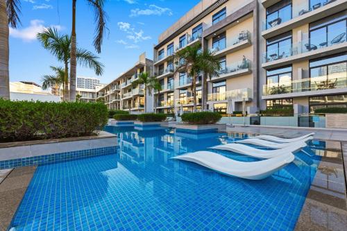 a swimming pool with a resort building in the background at Dubai JVC - Oxford Residence 2 - Parking&Balcony in Dubai