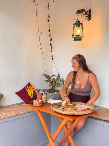 una mujer sentada en una mesa con un plato de comida en Wave Loom Hostel Ahangama, en Ahangama