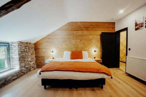 a bedroom with a bed and a stone wall at Les Landes de Bruyères in Waimes