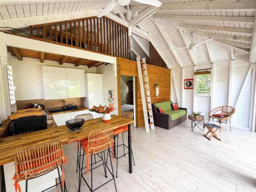 a kitchen and living room with a table and chairs at Au son des Grenouilles in Sainte-Rose