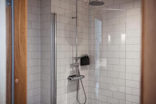 a bathroom with a shower with white tiles at Home Hotel Magasinet in Trelleborg
