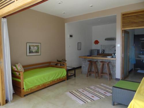 a living room with a green bed and a kitchen at Fler Payanke Apartment in Anse Royale