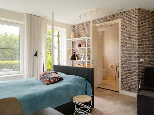 a bedroom with a bed and a brick wall at Sfeervolle Studio - Privéterras & Vloerverkoeling - Achterhoek in Almen