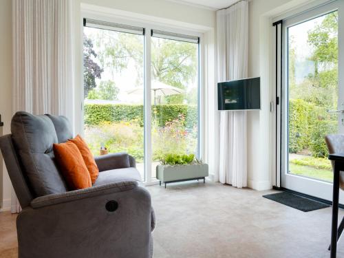 a living room with a couch and a large window at Sfeervolle Studio - Privéterras & Vloerverkoeling - Achterhoek in Almen