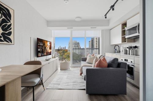 a kitchen and living room with a couch and a table at Cozy 2BR Condo with Free Parking & City Views in Toronto