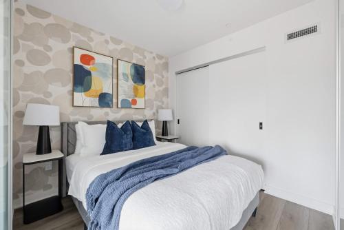 a bedroom with a white bed with blue pillows at Cozy 2BR Condo with Free Parking & City Views in Toronto