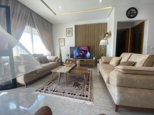ein Wohnzimmer mit Sofa und Fernseher in der Unterkunft Appartement coquet à Hammamet in Hammamet