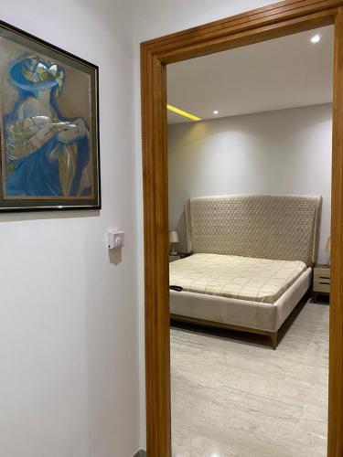 ein Zimmer mit einem Bett, einem Spiegel und einem Gemälde in der Unterkunft Appartement coquet à Hammamet in Hammamet