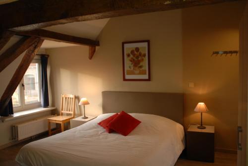a bedroom with a white bed with a red pillow at De Kruishoeve in De Haan
