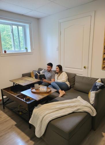 a man and woman sitting on a couch in a living room at Cozy 1BR in Vieux-Longueuil +parking 14min Downtown in Longueuil