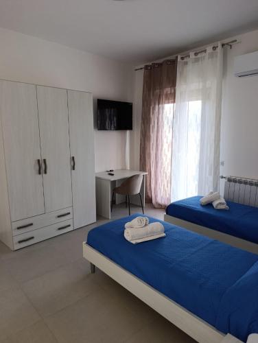a bedroom with two beds and a table and a desk at B&B al Vicolo in Nicosia