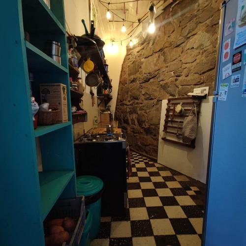 a kitchen with a checkered floor and a stone wall at Habitación en casa palmera Valparaiso in Valparaíso