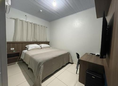una camera da letto con un letto e una televisione di Hotel Riviera a Aripuanã