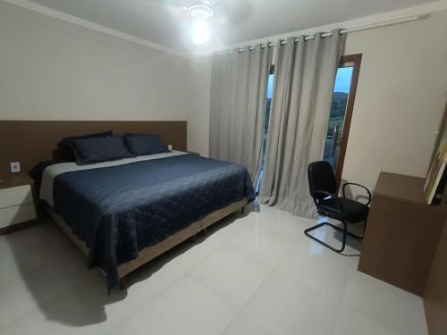 a bedroom with a bed and a chair and a window at Chácara Aricanga in Aracruz