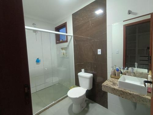 a bathroom with a toilet and a shower and a sink at Chácara Aricanga in Aracruz