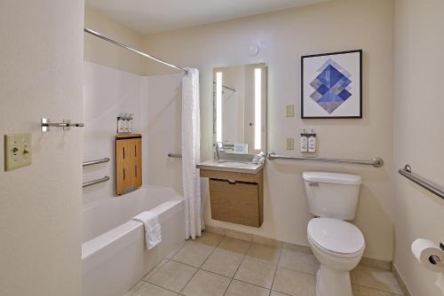 a bathroom with a toilet and a tub and a sink at Candlewood Suites - Peoria at Grand Prairie by IHG in Peoria
