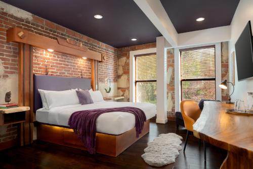 a bedroom with a bed and a brick wall at The Horton Hotel in Boone