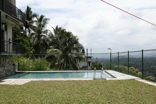 a swimming pool in front of a house with a fence at Cirute' Talwatte, Kandy in Kandy