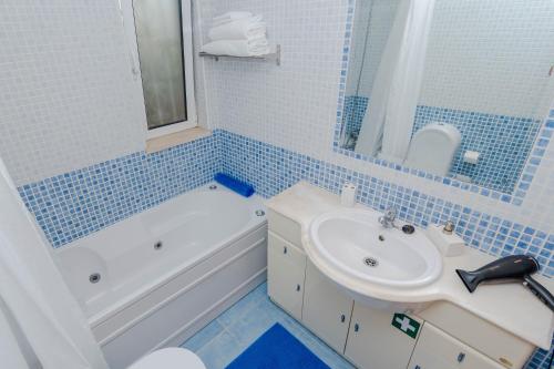 a blue tiled bathroom with a sink and a tub and a toilet at Ver o Mar in Albufeira