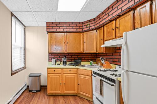 a kitchen with wooden cabinets and a white refrigerator at Classic American-style, 18 min to NYC in Carlstadt