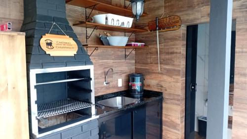 a kitchen with a sink and a stove at Cantinho das Palmeiras em Itapoá- Casa c piscina p 6 pessoas in Itapoa