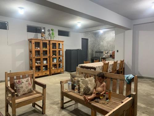 Ein kleines Kind sitzt auf zwei Holzstühlen in einem Zimmer in der Unterkunft Estância Malucos do Vale in Delfinópolis