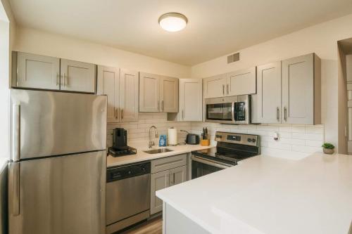 a kitchen with white cabinets and a stainless steel refrigerator at 2BR w King Bed Pool Steps to Forest Park CWE in Tower Grove